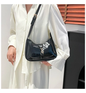 Close-up of black patent leather hobo bag featuring a gold piston clasp and sleek glossy finish
