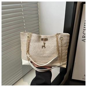 Detail of cream straw tote bag with gold deer pendant and chain strap for summer