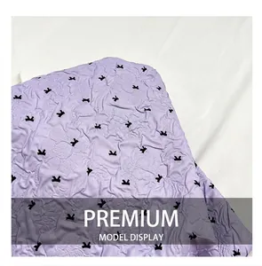 Detail shot of purple quilted fabric featuring a small black bow pattern and texture