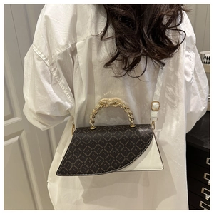 Detail view of the asymmetric crossbody bag with twisted gold handle and monogram pattern