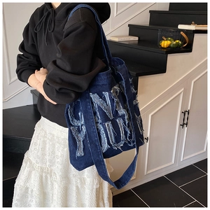 Close-up of blue denim tote bag featuring ONLY YOU frayed lettering and casual street style