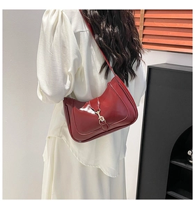 Détail du sac sous l'aisselle en cuir verni bordeaux avec fermoir piston doré