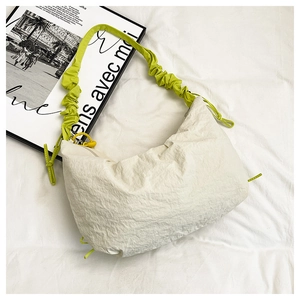 Détail du sac dumpling blanc cassé avec bandoulière plissée verte et tissu texturé