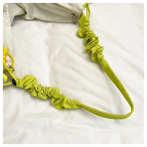 Détail du sac à bandoulière beige avec texture de sangle froncée vert vif contrastante