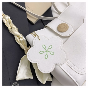 Détail de sac à main blanc en cuir grainé avec foulard en soie et boucle en bois