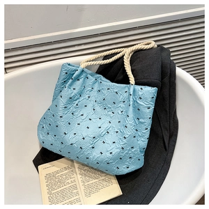 Close-up of light blue pleated tote bag with black bow prints and cotton rope handles
