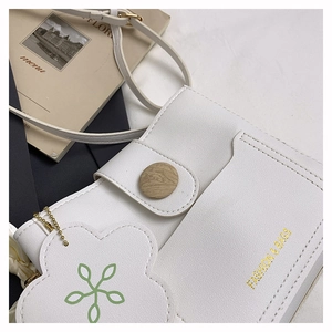 Détail du sac bandoulière en similicuir blanc avec boucle bois et breloque fleur