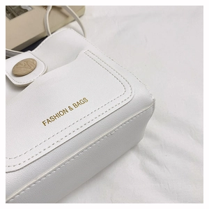 Détail d'un sac en cuir PU blanc avec boucle ronde en bois et logo doré