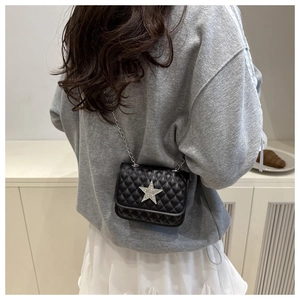 Close-up of a mini black quilted crossbody bag featuring a silver glitter star decoration