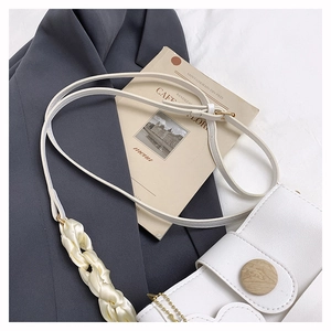 Détail du sac en cuir blanc avec bandoulière en soie et bouton en bois décoratif