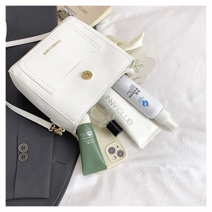 Vue intérieure du sac bandoulière en cuir blanc montrant les essentiels du quotidien