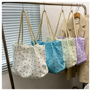 Detail of four colorful tote bags with textured fabric and rope handles on display