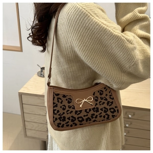 Close-up of leopard print underarm bag with gold bow buckle on beige knit sweater