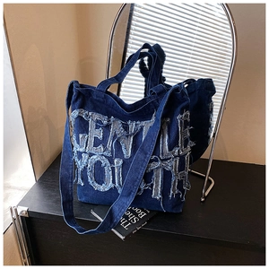 Close-up of Gentle Youth denim tote bag with raw-edge letters and versatile straps
