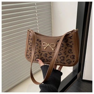 Close-up of leopard print shoulder bag with golden bow buckle and brown leather