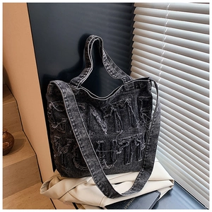Detail of black denim tote bag with frayed letter design and vintage street style