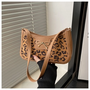 Detail of the leopard print panel and golden bow buckle on a brown leather shoulder bag