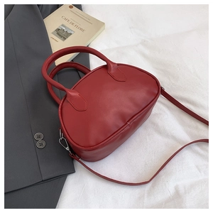 Detalle del bolso de mano minimalista rojo de cuero con forma de píldora y cremalleras