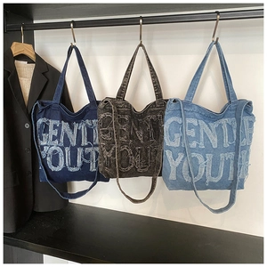 Detailed view of denim tote bags in three colors featuring Gentle Youth frayed lettering
