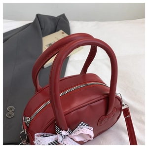 Detalle de bolso retro rojo con colgante de lazo a cuadros y acabado elegante