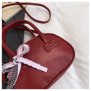 Detalle de bolso rojo de cuero con lazo de encaje rosa y asas con relieve elegante