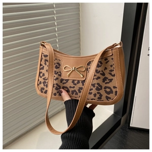 Close-up of leopard print baguette bag with brown leather trim and golden bow buckle
