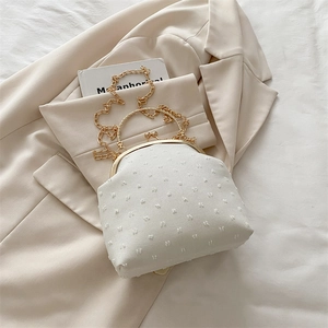 Détail du sac à main en tissu blanc à pois avec fermoir doré élégant et poignée en métal