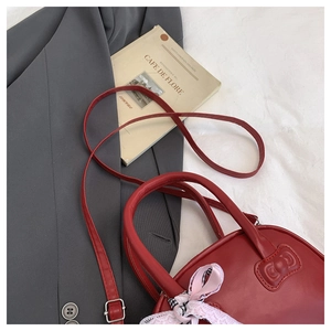 Detalle del bolso rojo con lazo, asa con cinta de satén y textura acolchada elegante