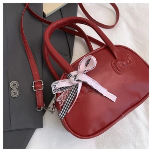 Detalle de bolso rojo de cuero con lazo y conector de correa con forma de gatito
