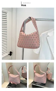 Détail du sac hobo rose avec des clous argentés sur le cuir à grain de lychee de qualité