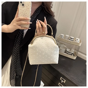 Sac bandoulière rétro crème avec texture en relief et fermoir doré porté par mannequin