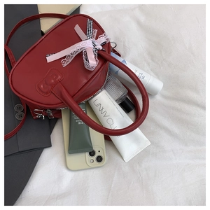 Detalle de mini bolso rojo de PU con costura de lazo y cinta de encaje rosa suave