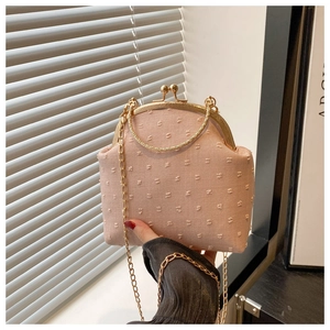 Détail du sac à main en tissu rose texturé avec poignée dorée et fermoir en métal chic