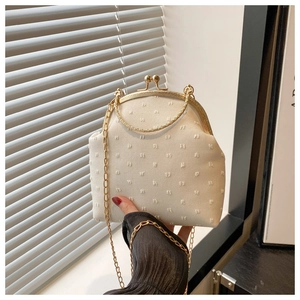 Détail du sac vintage crème avec poignée anneau dorée et tissu à texture de perles fines