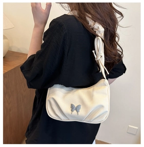 Détail du sac croissant en toile avec décor papillon argenté et bandoulière plissée