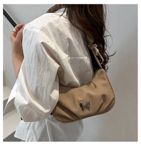Detail of khaki corduroy crescent bag with silver butterfly and knotted strap design