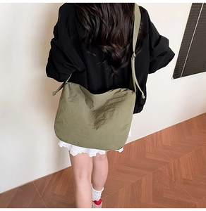 Detailansicht einer olivgrünen Umhängetasche aus Nylon im Falten-Design am Modell