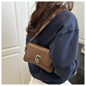 Detailed side view of vintage brown leather crossbody bag with oval metal lock