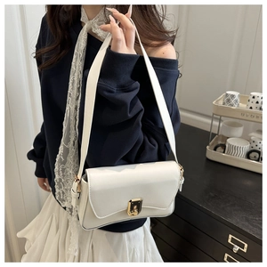 Detailed view of white faux leather bag featuring golden lock and lace ribbon detail