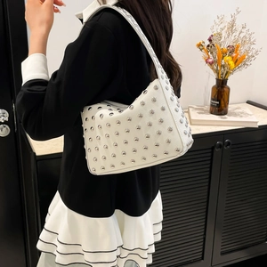 Sac sous le bras en cuir blanc avec rivets argentés porté par un mannequin femme