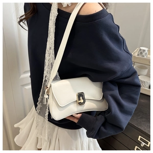 White faux leather crossbody bag with metal rotary lock shown on model indoors