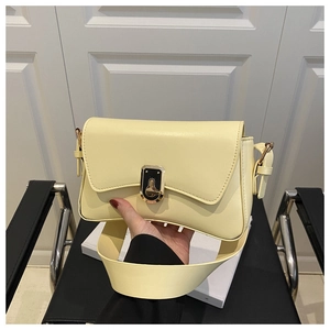 Détail d'un sac bandoulière en cuir jaune pâle avec une boucle en métal doré poli