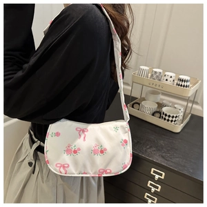Dettaglio di una borsa baguette bianca con stampe di rose rosa e piccoli fiocchi