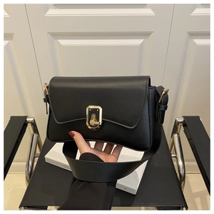 Gros plan sur un sac bandoulière en cuir noir avec une boucle en métal doré poli