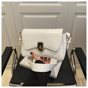 Détail d'un sac bandoulière en cuir blanc crème avec un fermoir tournant rectangulaire doré
