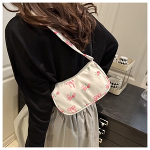 Dettaglio della borsa a spalla bianca con stampe di rose e fiocchi rosa