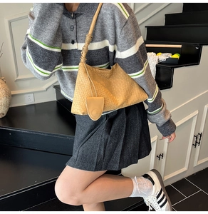 Détail de la texture tressée et du nœud sur un sac à bandoulière hobo marron pour femme