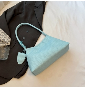 Détail du sac à bandoulière tressé bleu clair avec breloque mini porte-monnaie assortie