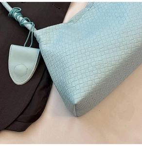 Détail du sac à main tissé bleu clair avec poignée en corde torsadée et breloque en cuir