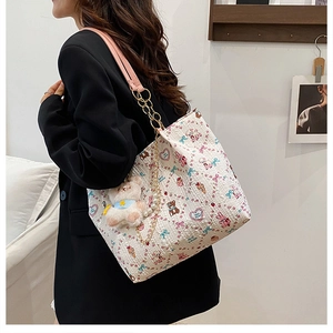 Detail of white tote bag with pink cartoon patterns, metal chain strap and plush bear charm